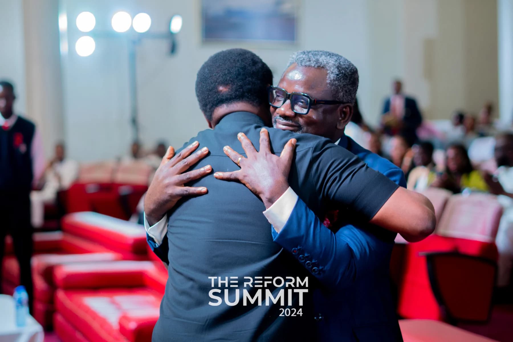 Two attendees greeting warmly inside The Reform Summit